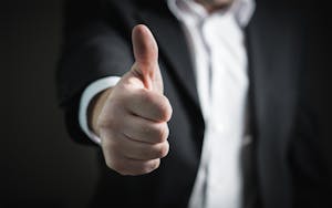 Home 9 A close-up of a man's thumbs up gesture, symbolizing success and agreement.